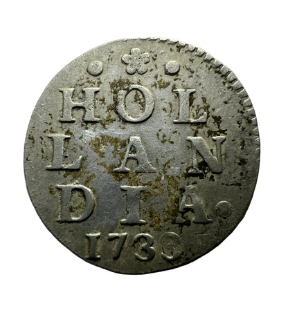 An antique circular silver coin featuring the text 'HOLLANDIA 1736' with a small crown emblem at the top.